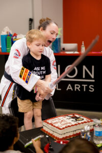 boy cutting birthday cake with a sword